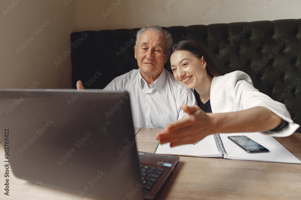 Senior with a young assistant. Businessman working in the cafe. Man in a white shirt. Young woman with her boss. Senior with a young assistant. Businessman working in the cafe. Man in a white shirt. Young woman with her boss.