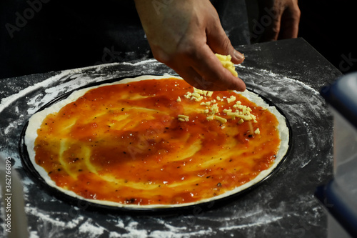 Tomato sauce and butter cheese on top pizza dough garnish with quality ingredients.. An important trick for making tasty and appetizing pizza is to prepare quality pizza dough and sauces.