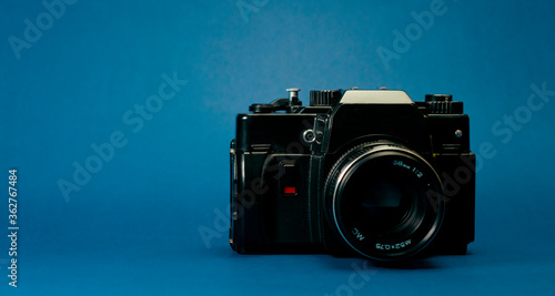 Analog black photography camera on a blue background