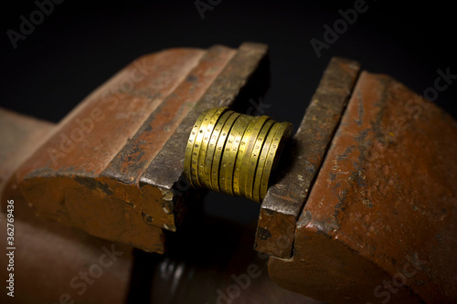 A few coins in a metal vise. Concept of economic problems. Selective focus.
