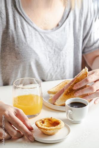 Woman eating Portuguese breakfast. Black coffee bica  sandwich mixto  pastel de nata and orange juice