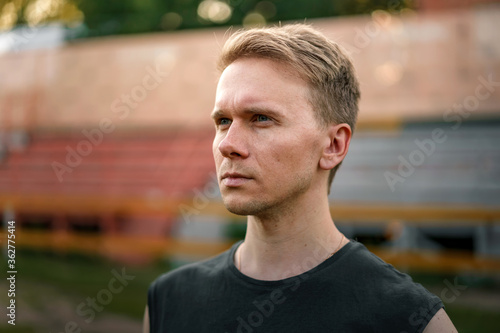 Portrait of a Young man at the stadium against the background of the sports stands, a purposeful look at the stadium