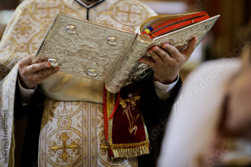 Photo Details of an Orthodox priest reading from the Holy Bible during an Orthodox Baptism