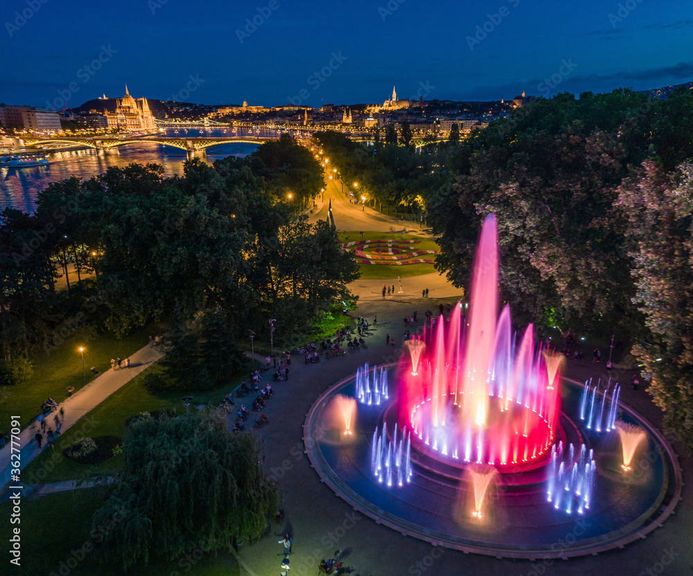 Obraz premium Budapest, Hungary - Aerial view of the Margaret Island Musical Fountain at dusk with Parliament building, Fisherman's Bastion and Buda Castle Royal Palace at background