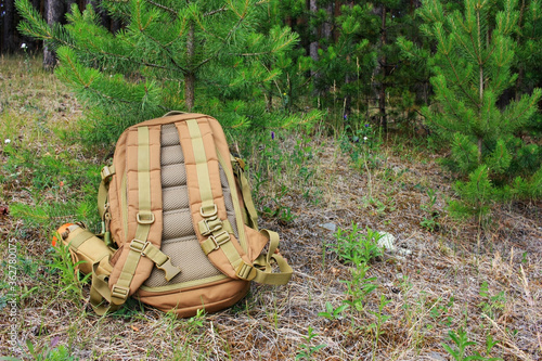 Tactical backpack lies on the ground in the forest.