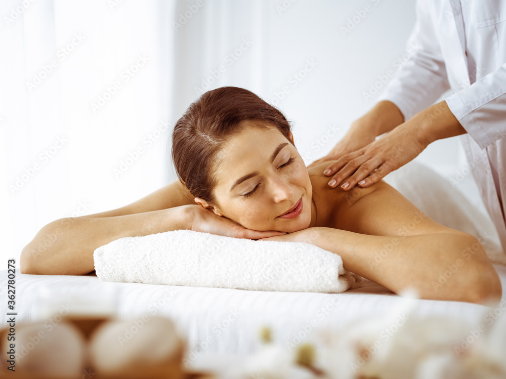 Beautiful brunette woman enjoying back massage with closed eyes. Spa and medicine concept Beautiful brunette woman enjoying back massage with closed eyes. Spa and medicine concept