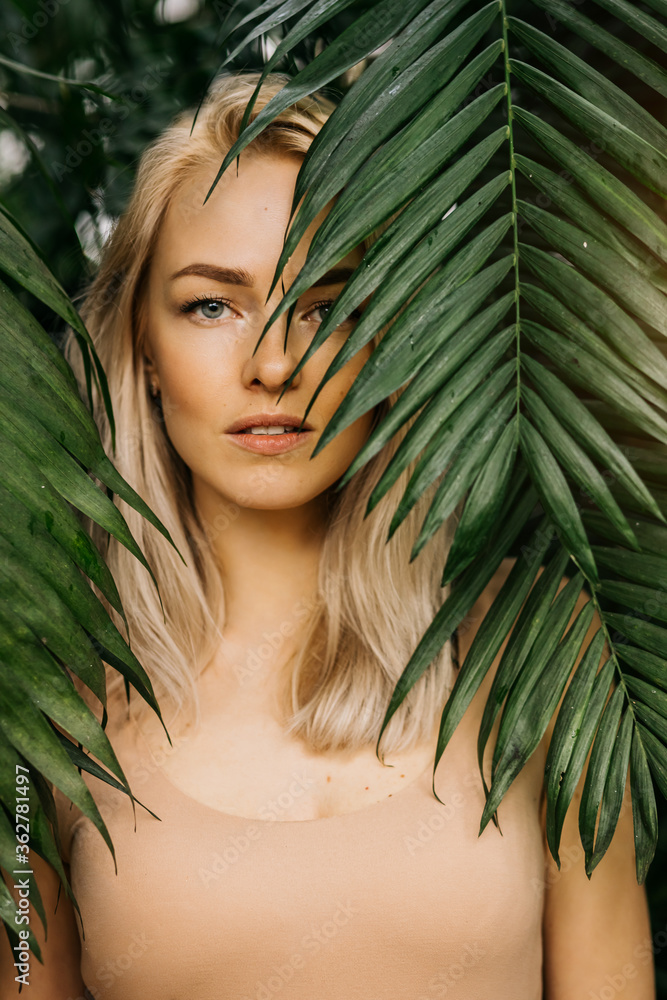 Fototapeta premium Woman in swimsuit on tropical plants background