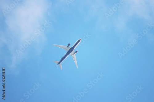 Airplane flying in the blue sky with white clouds, bottom view. Two-engine commercial plane after taking off