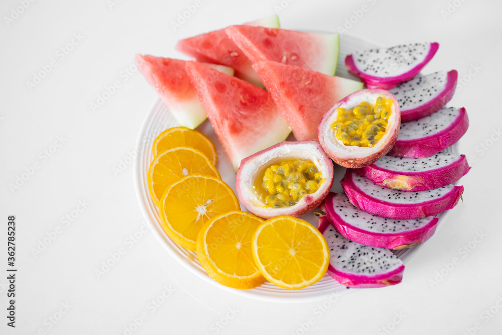 White plate of sliced fruit. Fresh fruits and vitamins. Still life colored summer fruits. White plate of sliced fruit. Fresh fruits and vitamins. Still life colored summer fruits.