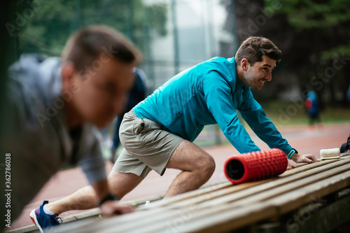 Young men exercising on a race track. Two young friends training outdoors. 