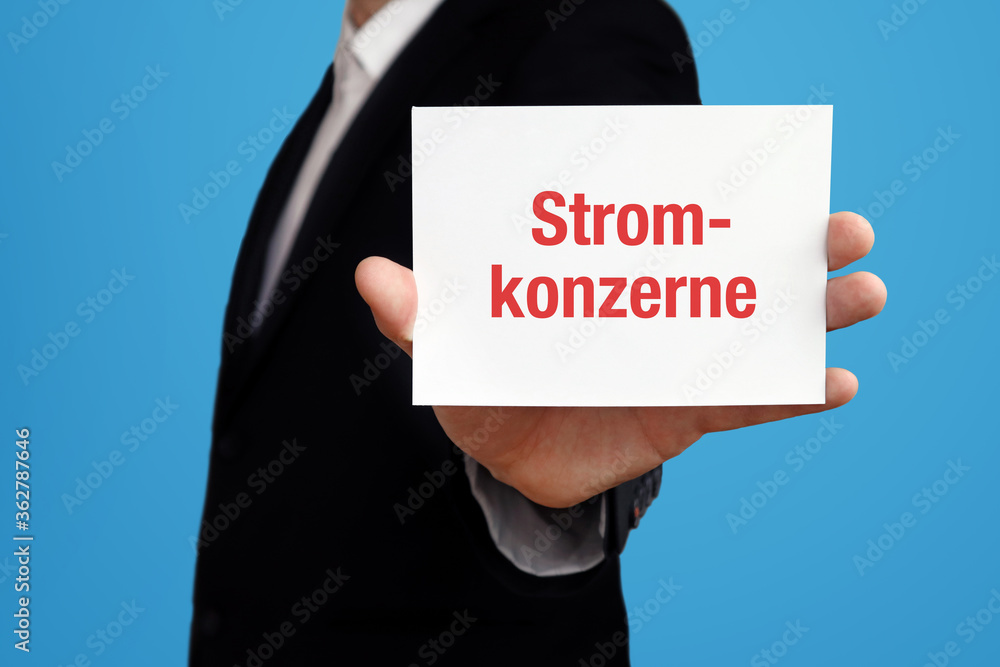 Stromkonzerne. Geschäftsmann im Anzug hält Karte in die Kamera. Der Begriff Stromkonzerne steht im Schild. Symbol für Business, Finanzen, Statistik, Analyse, Wirtschaft