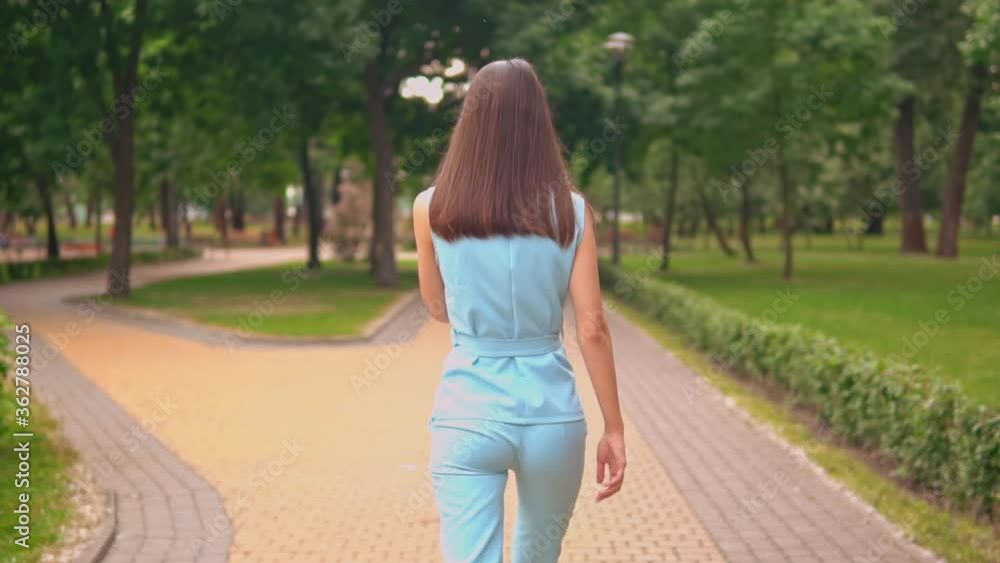 businesswoman in blue suit using smartphone walking on the street in summer city park slow motion businesswoman in blue suit using smartphone walking on the street in summer city park slow motion