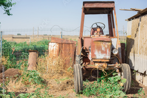 An old rusty tractor in the back yard of a poor village