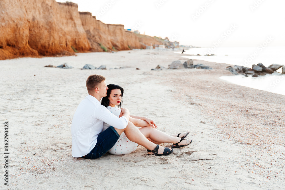 Loving couple in white clothes during a honeymoon at sea walk on the sand at a photoshoot Love Story, ocean coast, beach