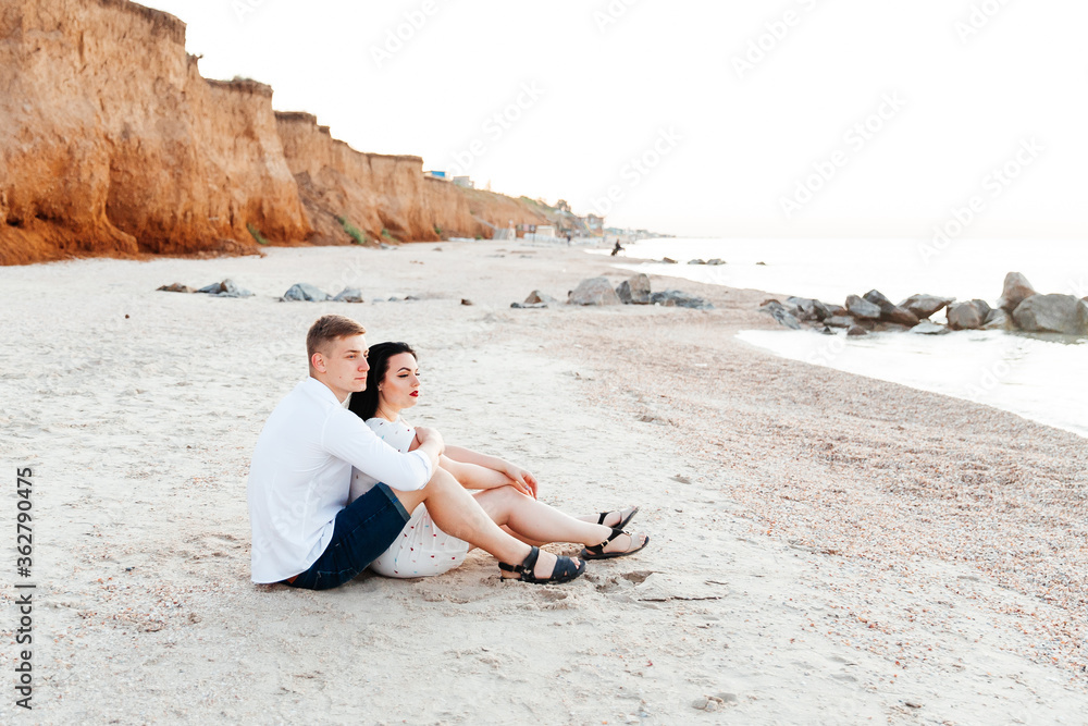 Loving couple in white clothes during a honeymoon at sea walk on the sand at a photoshoot Love Story, ocean coast, beach