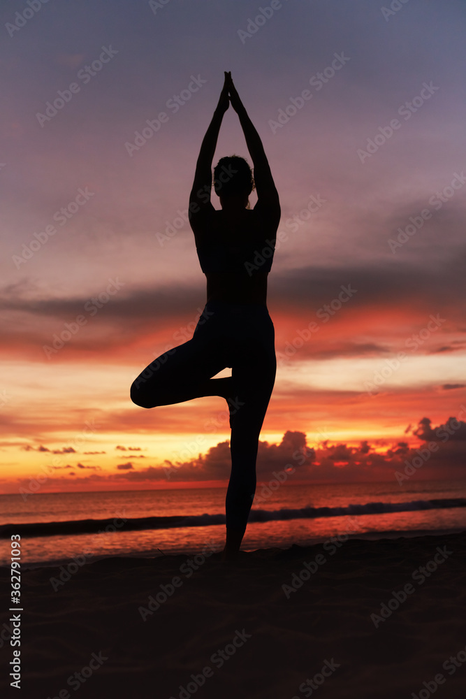 Yoga Poses. Woman Practicing Vrikshasana On Ocean Beach. Female Silhouette Standing In Tree Pose Balancing Asana At Beautiful Sunset. Yoga As Exercise For Lifestyle.