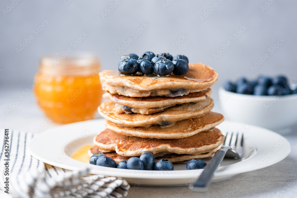 Whole wheat pancakes with blueberries and honey on a plate. Tasty breakfast food, stack of homemade pancakes Whole wheat pancakes with blueberries and honey on a plate. Tasty breakfast food, stack of homemade pancakes