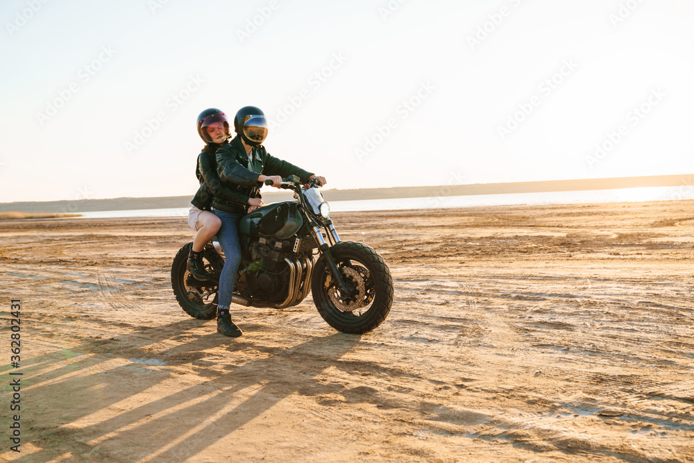 Beautiful young stylish couple enjoying ride on a motorbike Beautiful young stylish couple enjoying ride on a motorbike
