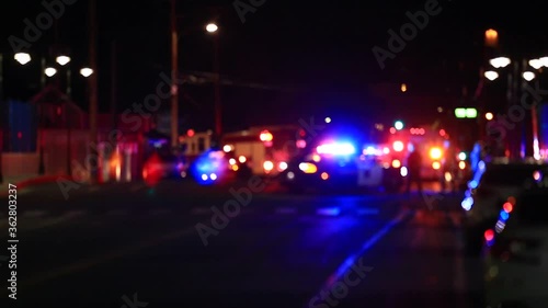 Defocused scene lights flashing fire trucks and police cars people standing in street.