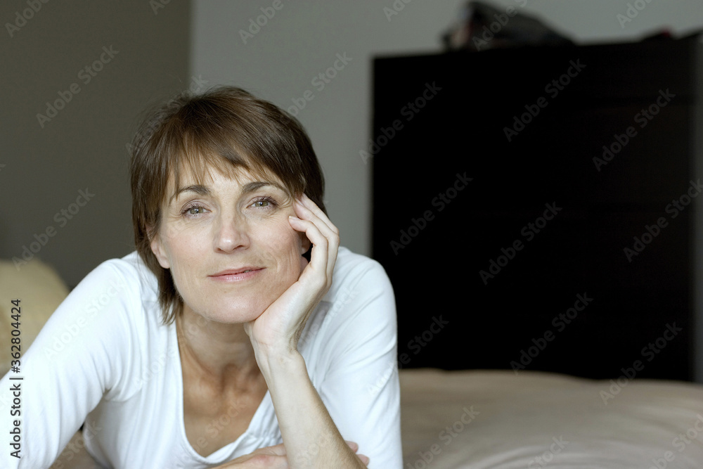 Woman lying forward on the bed smiling at the camera Woman lying forward on the bed smiling at the camera