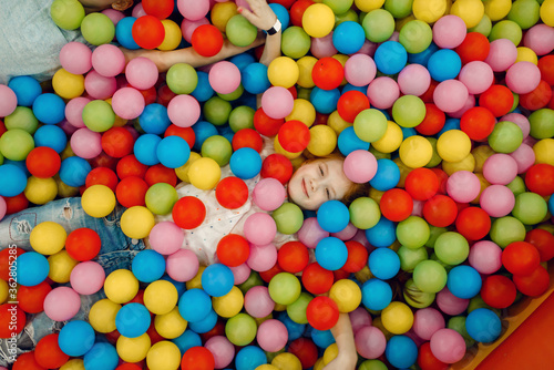 Girl lying among many colorful balls  playground