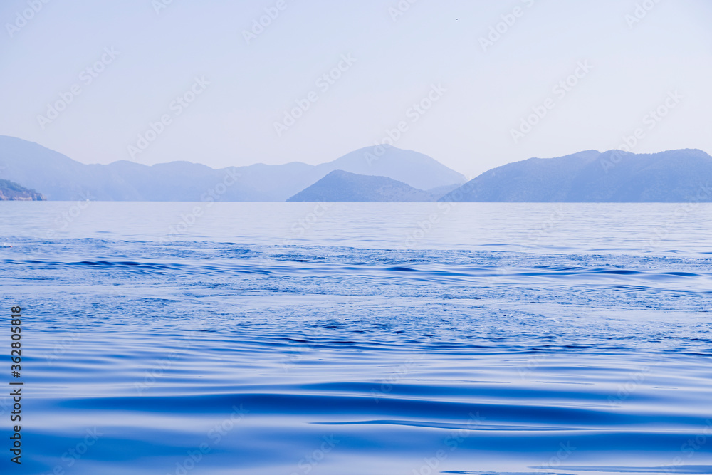 Peaceful seascape. Beautiful blue sky over calm sea with sunlight reflection. Waves. Tranquil harmony.