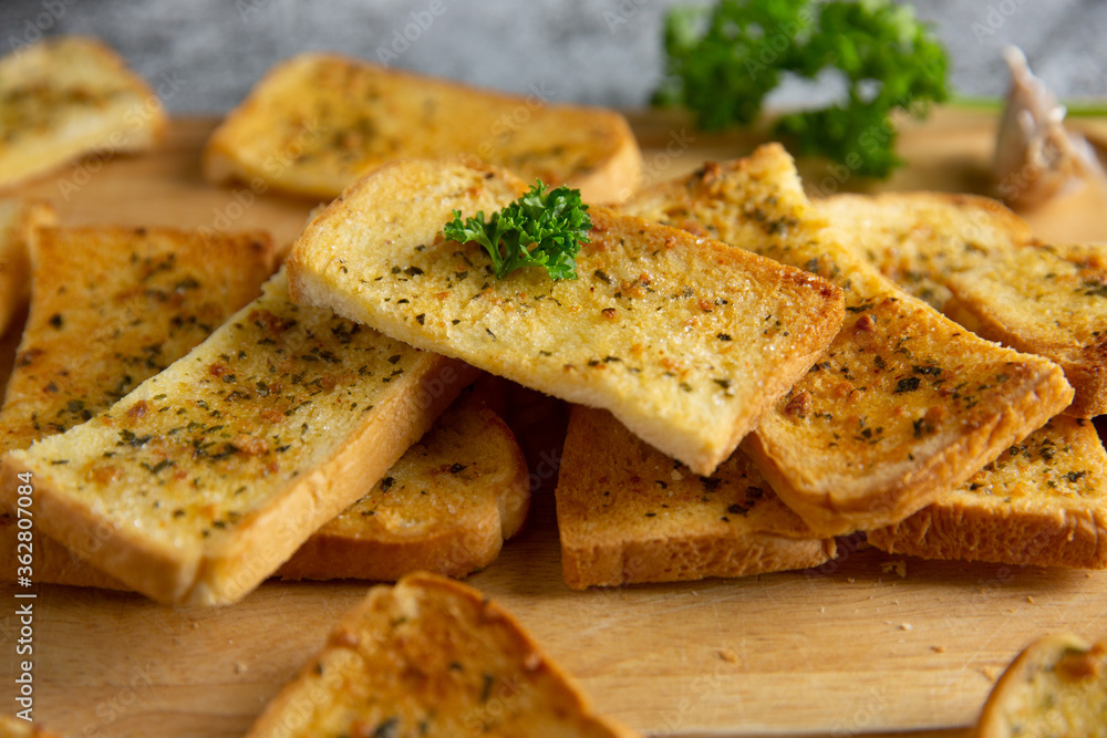 Wooden cutting board with delicious homemade garlic bread on the cement floor