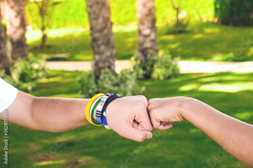Two brothers or friends bumping fists outside on green grass background. Love and family concept, unity.