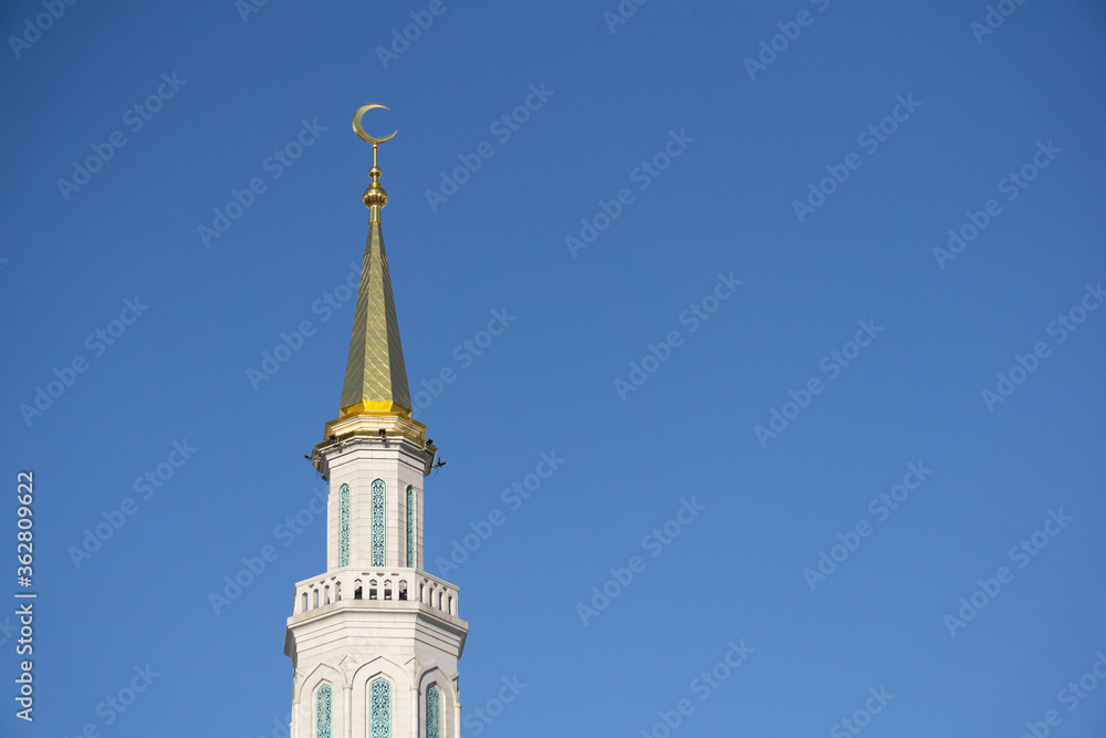 Minaret of a Muslim mosque on a background of blue sky. Muslim and Islamic architecture