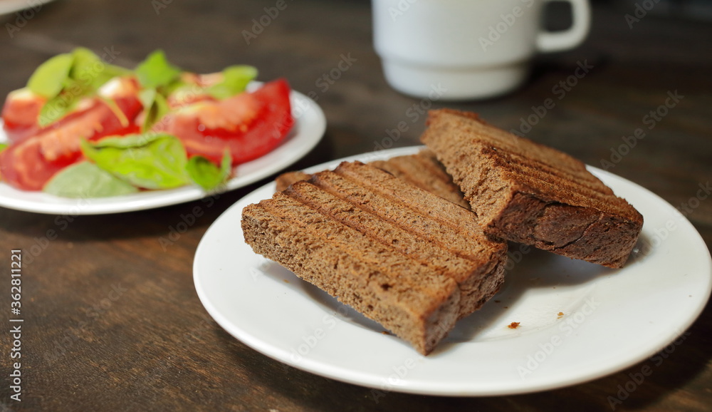 Fresh bread toast. Sliced tomatoes with lettuce on a white plate. Healthy eating concept Fresh bread toast. Sliced tomatoes with lettuce on a white plate. Healthy eating concept