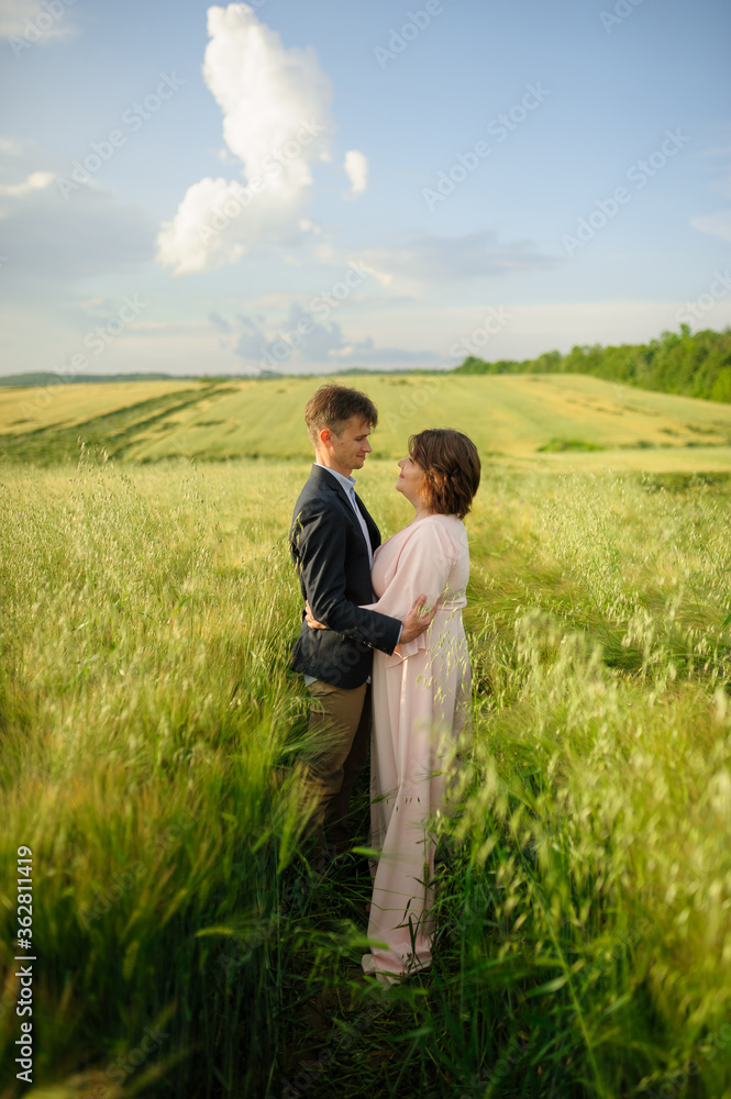 Adult couple in a green wheat field.