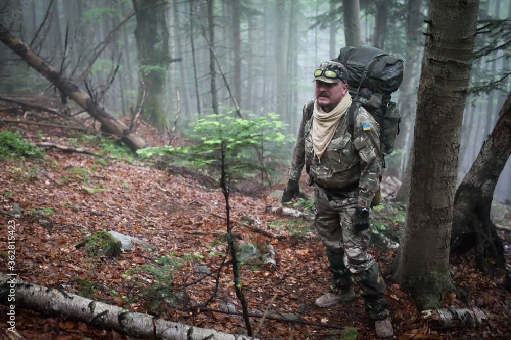 Active healthy man in camouflage hiking in beautiful forest