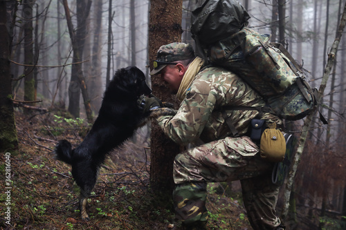 Active healthy man hiking with dog in beautiful forest