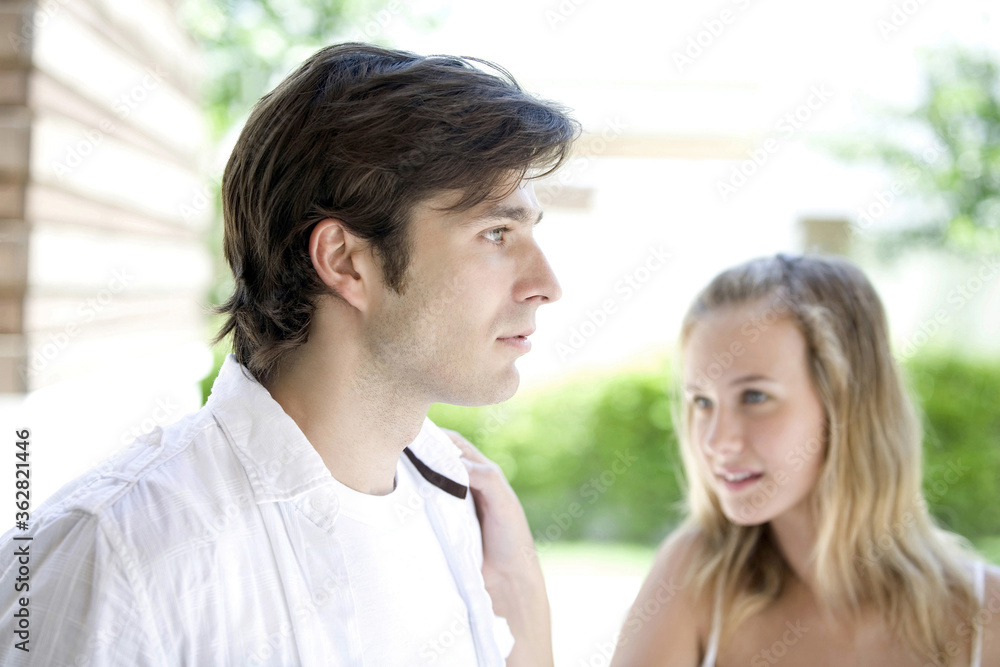 Man looking away, woman in the background