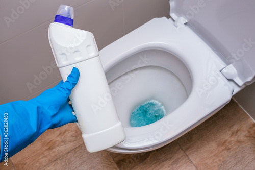 Fototapeta Naklejka Na Ścianę i Meble -  Clean toilet with cleaning agent bleaching gel and a gloved hand