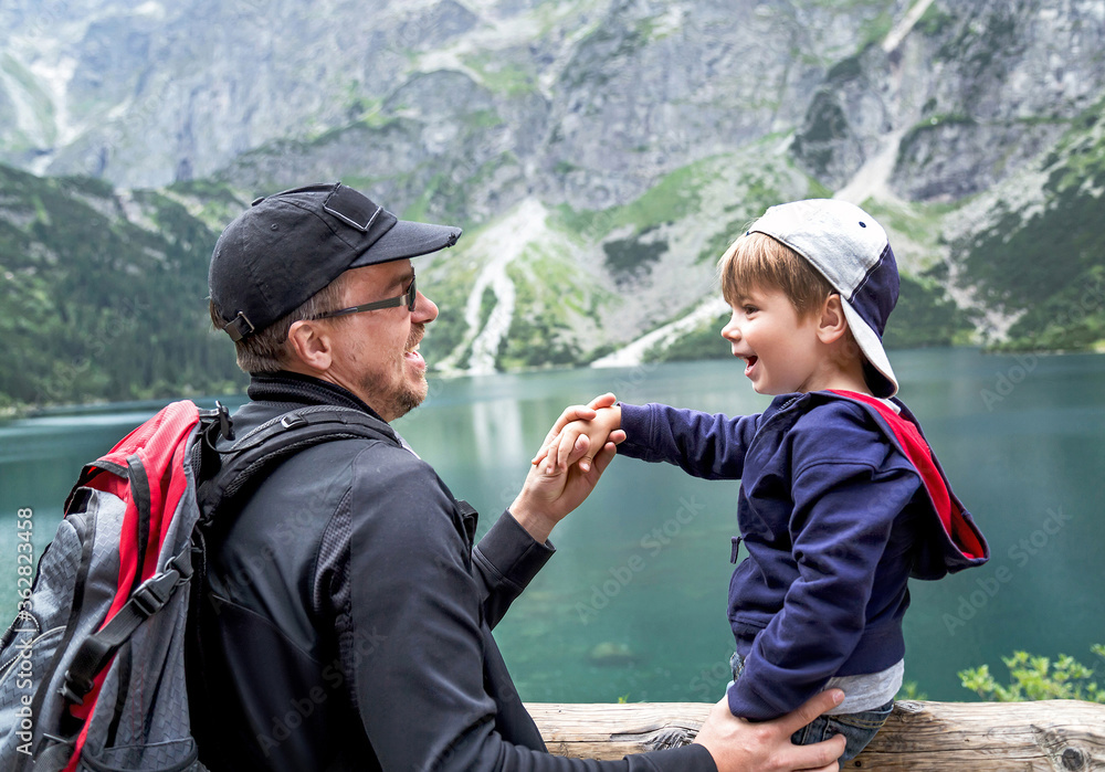 Happy joyful father and his son having fun near the Eye of the Sea lake (Morskie Oko ) in Tatra mountains. Poland.