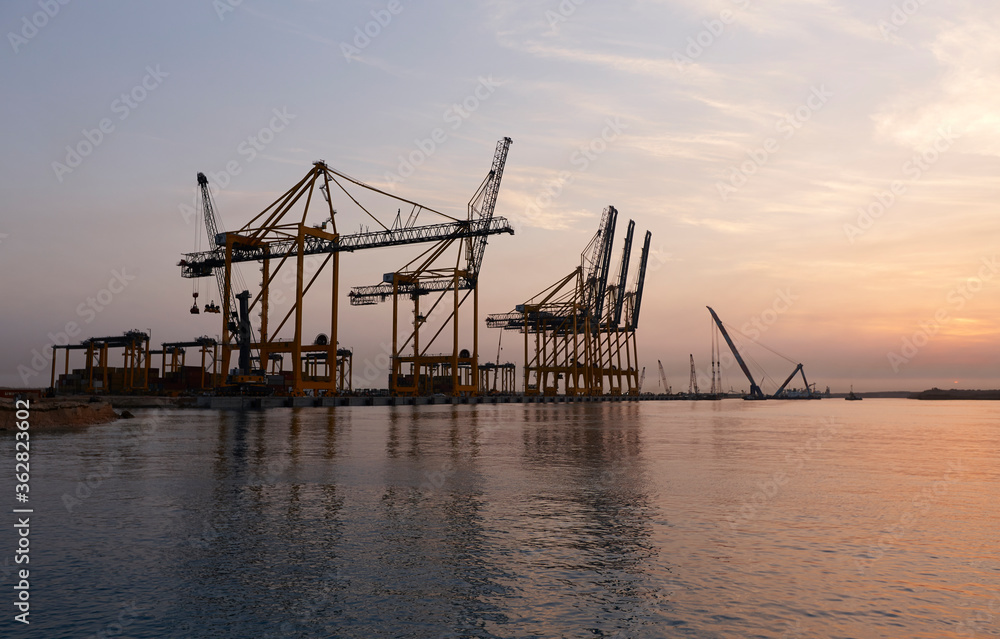 Cranes in seaport at sunrise.