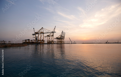 Cranes in seaport at sunrise. © Leap Studios