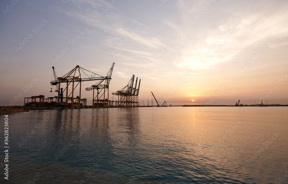 Cranes in seaport at sunrise.