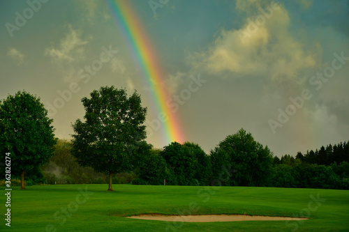 beautiful rainbow over a golf course , forest, meadow