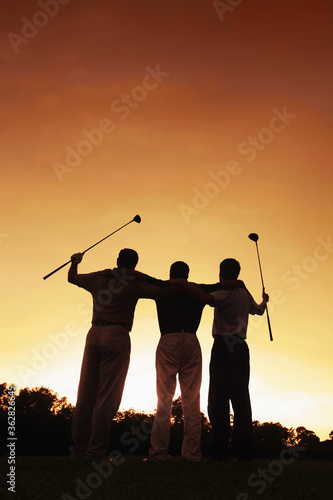 Three men at golf course during sunset