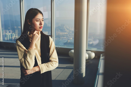 Young confident Japanese office worker of big successful model agency is thinking about upcoming show, while is standing in modern skyscraper interior near copy space for your advertising text message Free Download Young confident Japanese office worker of big successful model agency is thinking about upcoming show, while is standing in modern skyscraper interior near copy space for your advertising text message - GFXLoad