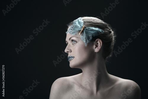 Woman with rhinestones on her lips and butterfly decorating her hair