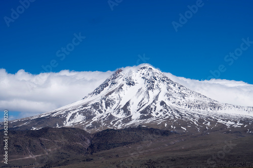 A snowy mountain peak  cloudy blue sky  
