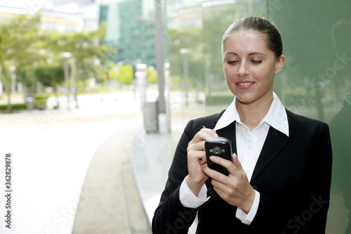 Businesswoman smiling while text messaging on the phone
