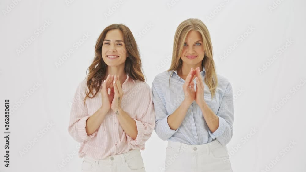 Two attractive women are plotting something crazy standing isolated over white background in studio Two attractive women are plotting something crazy standing isolated over white background in studio