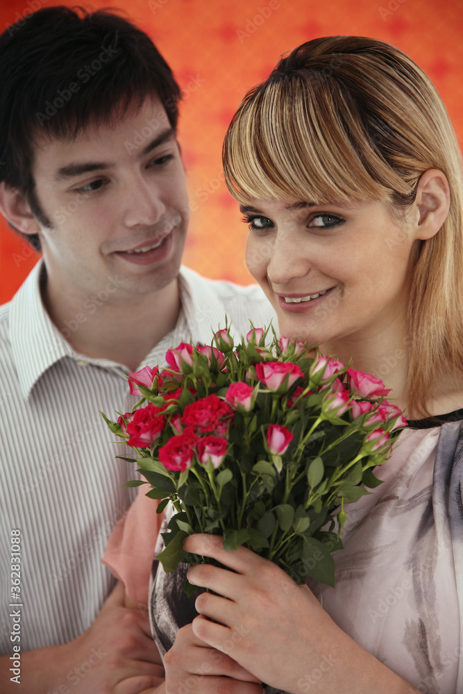 Woman holding a bouquet of flowers, man looking at her