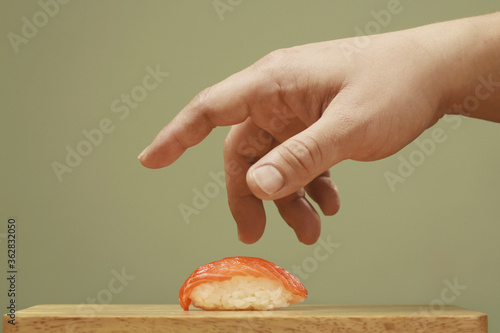 Man taking sushi from chopping board