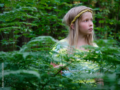 Fototapeta Naklejka Na Ścianę i Meble -  portrait of a blonde girl with blue eyes in green thickets