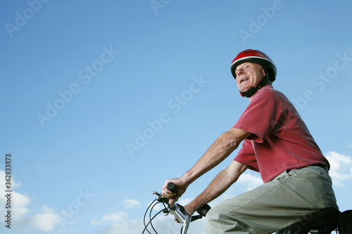 Senior man with helmet riding on bicycle